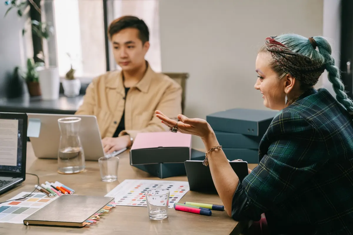 A small agency team sits around a table discussing a client project in a bright office.