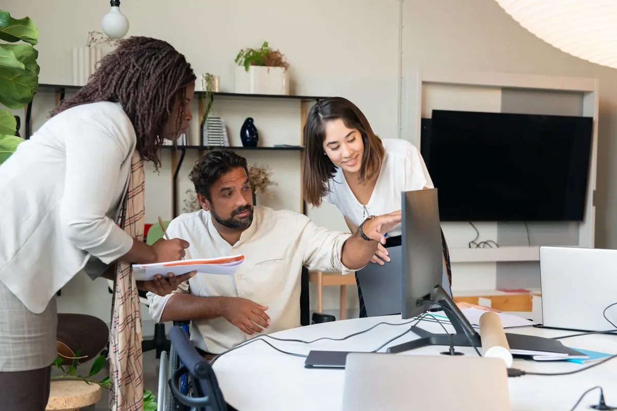 Two members of a small agency look over several client websites on computer monitors in an office.