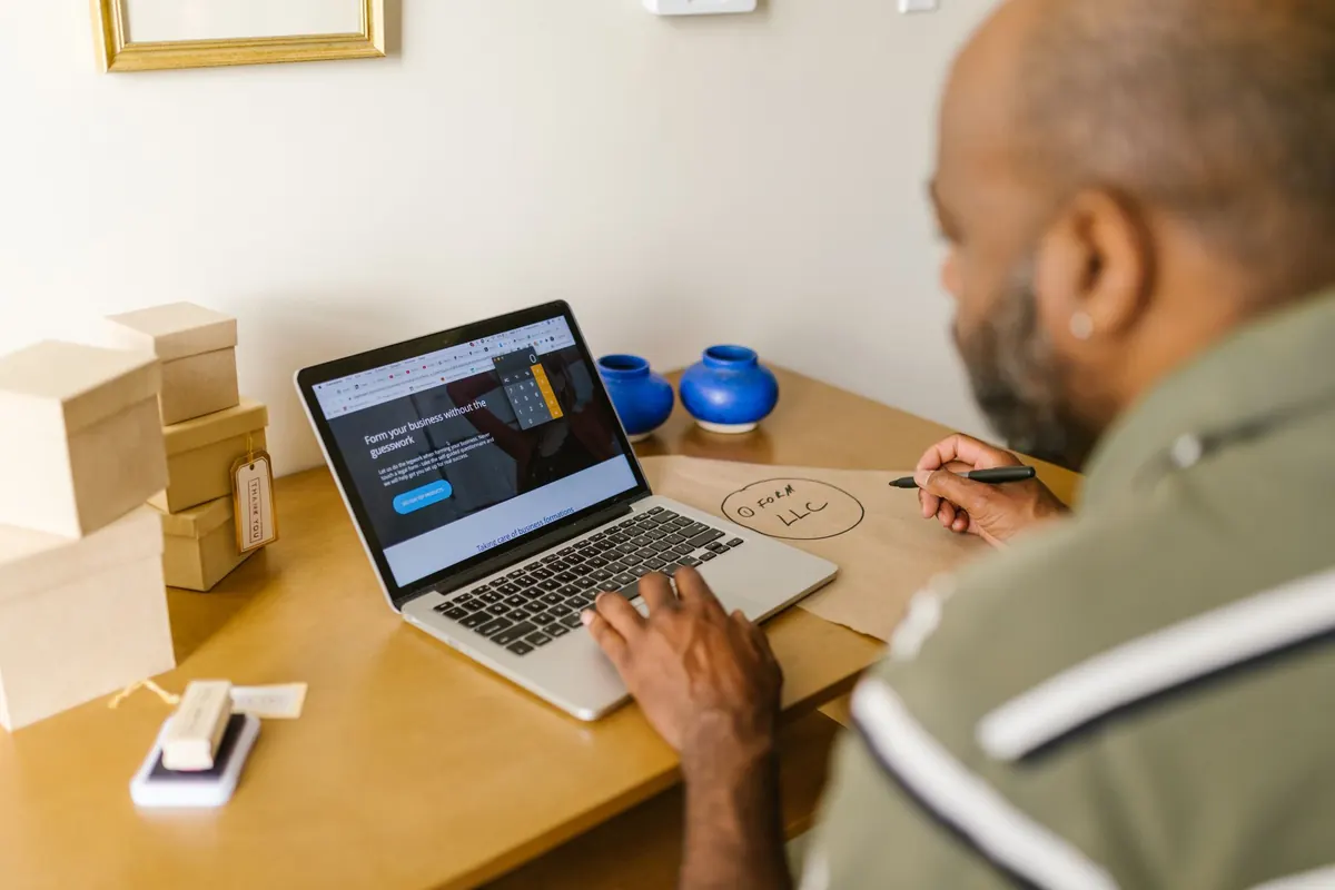 A small business owner works on a laptop at a cafe table, planning a new website.