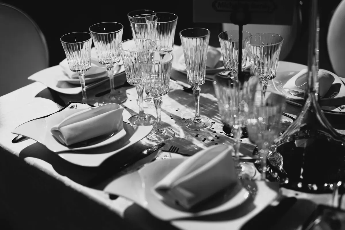 Reception tables laid with white linen, glassware and fresh flowers before the guests arrive.