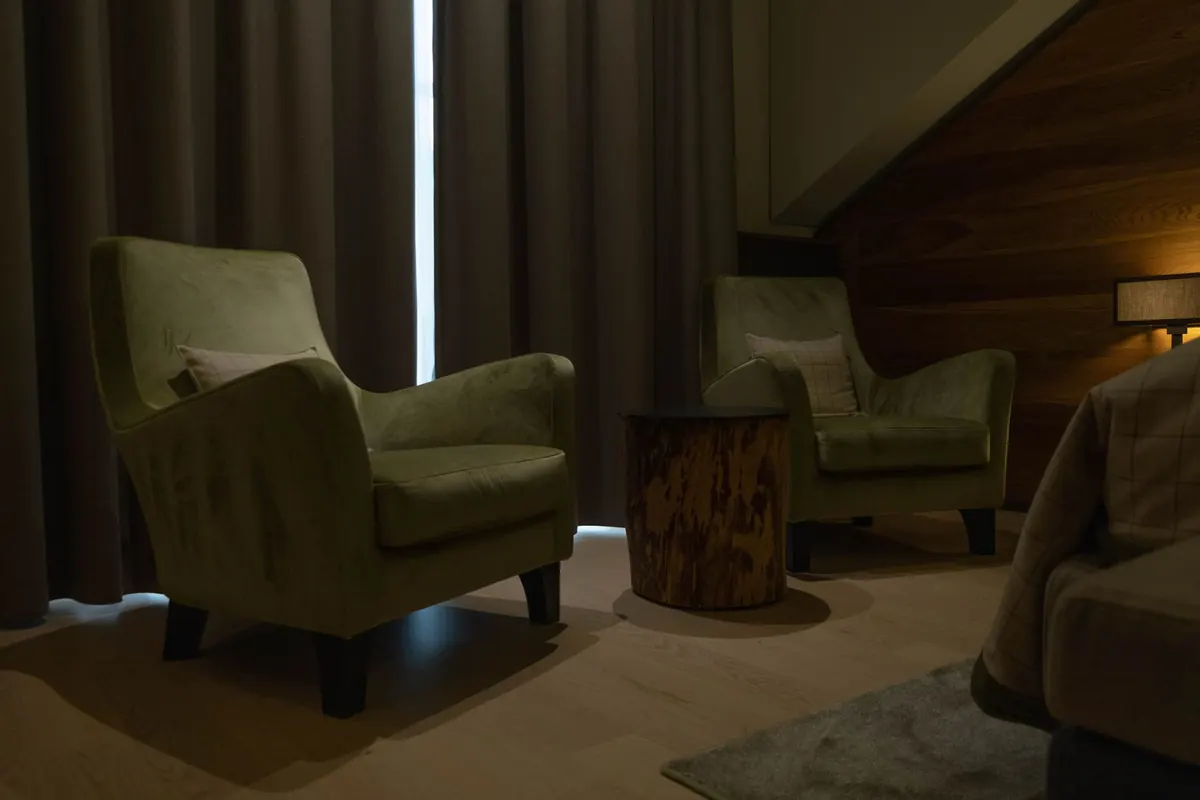 A calm therapy room with two armchairs, a low table and green plants beside a bright window.