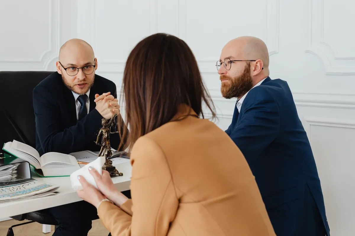 A lawyer sits across a desk from a client in a small office, going through documents together.