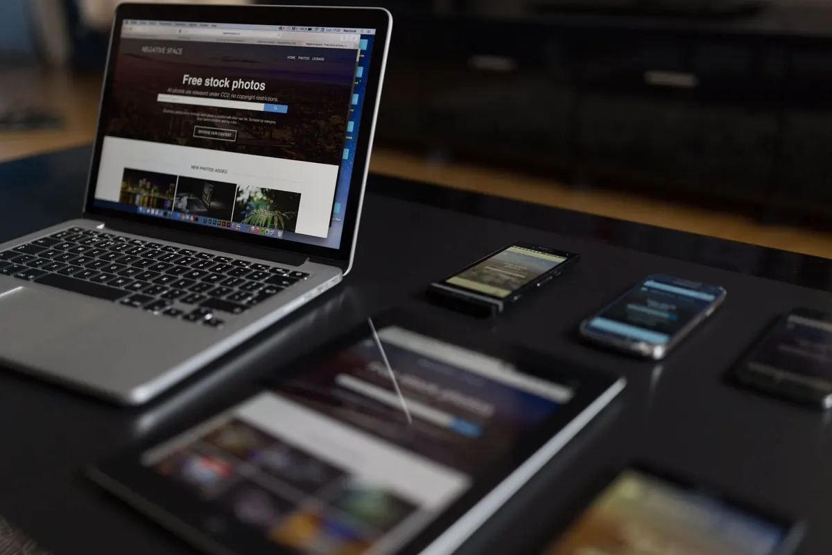 A web designer works on a laptop at a desk covered with sketches and handwritten notes.