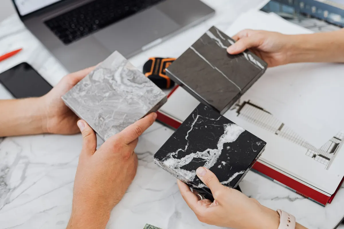 Two people review printed website layouts together across a table in a small studio.
