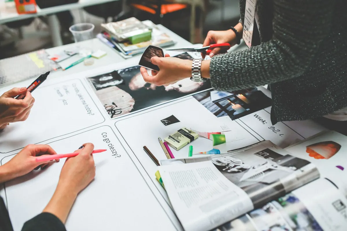 A small agency team talks through client projects around a table with open laptops.