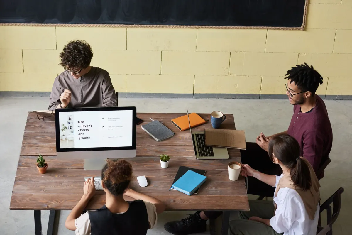 A small agency team gathered around a computer screen, talking through a website project.