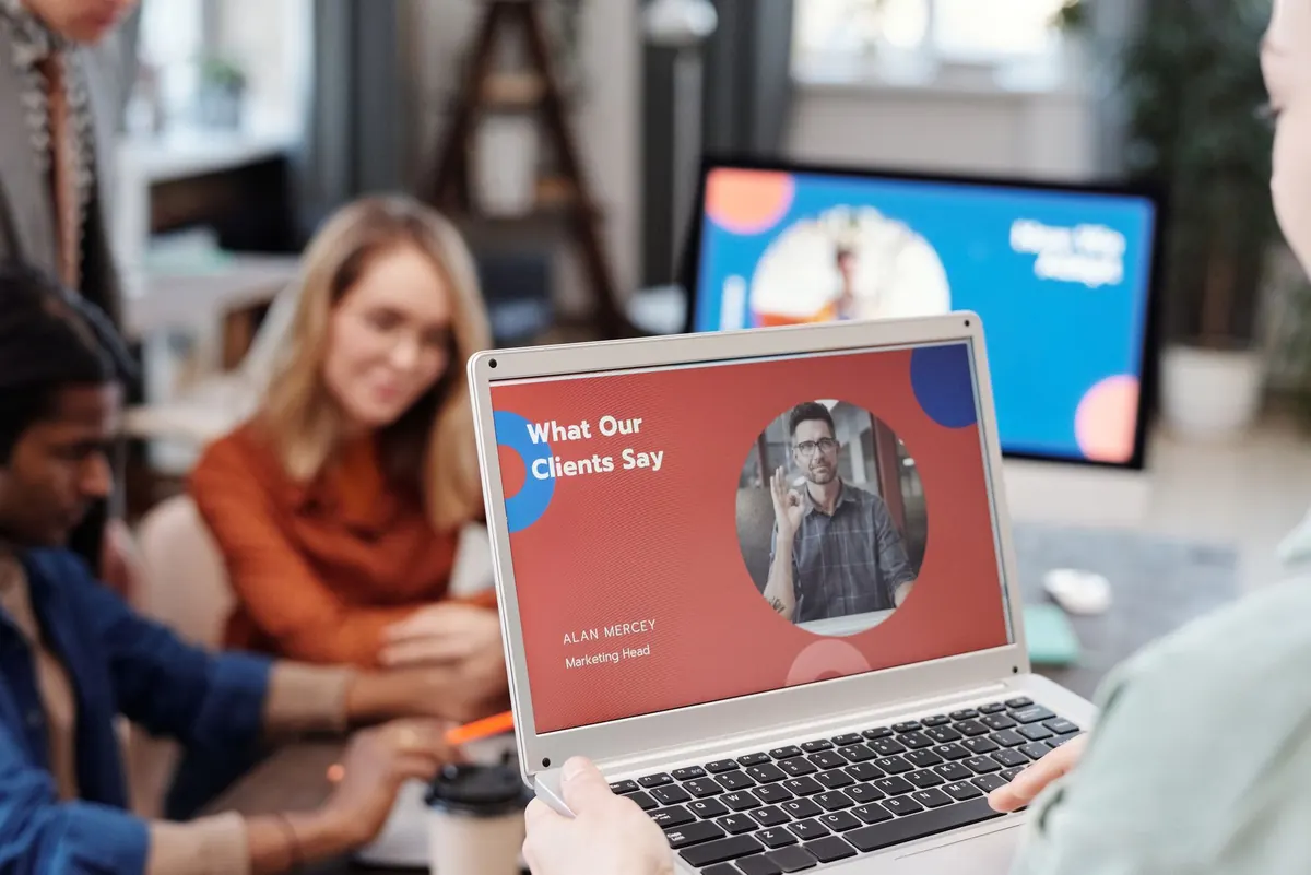 A small agency team looks over a client website on a laptop at a shared desk.