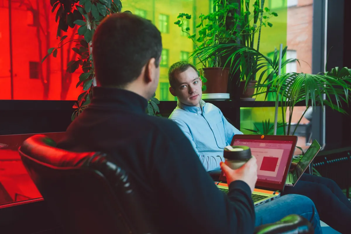 Two colleagues sitting together at a laptop reviewing client accounts in a small office.