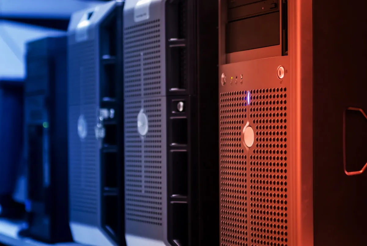 Rows of server racks with small status lights glowing along a data centre corridor.