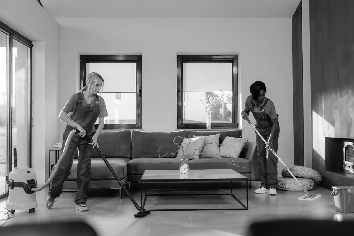 A commercial cleaner vacuuming the carpet in an empty open-plan office in the evening.