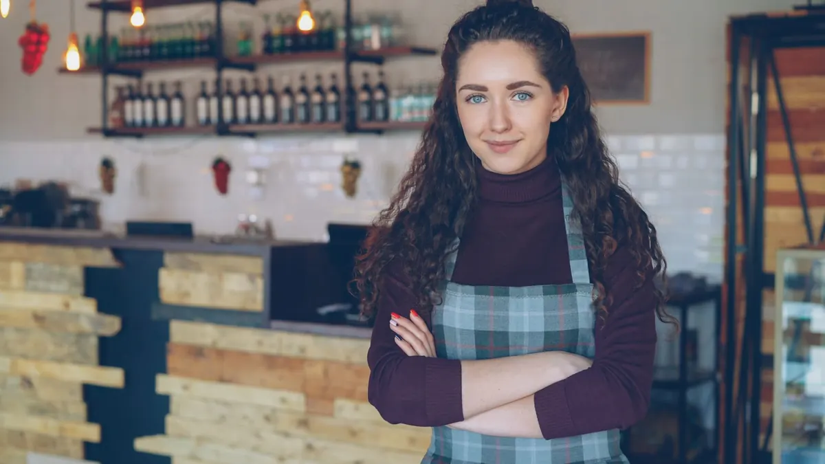 A small business owner sits at a café table, building a website on a laptop.