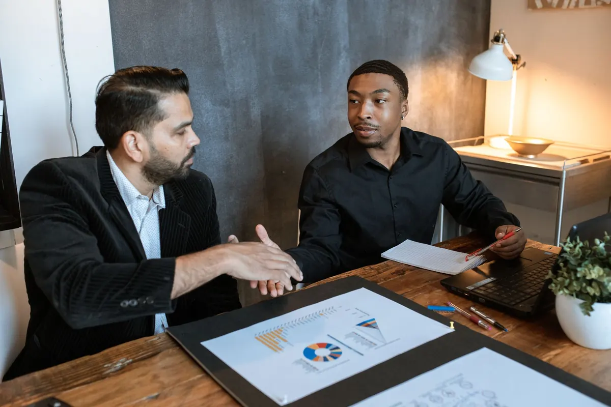 A consultant goes through a plan on a laptop with a small business owner at a desk.